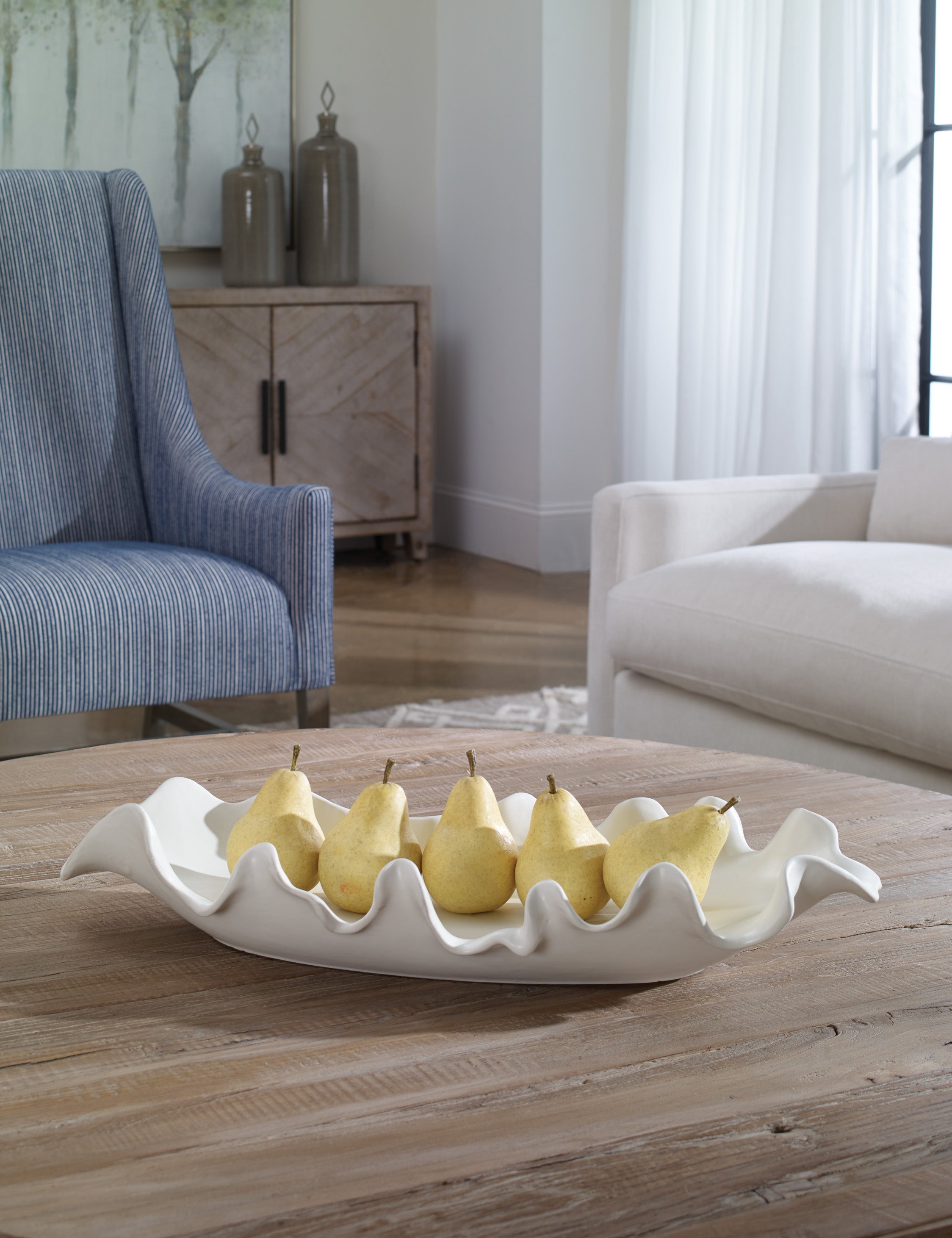 Beline low-profile ruffled long decorative bowl styled on a coffee table filled with pears.