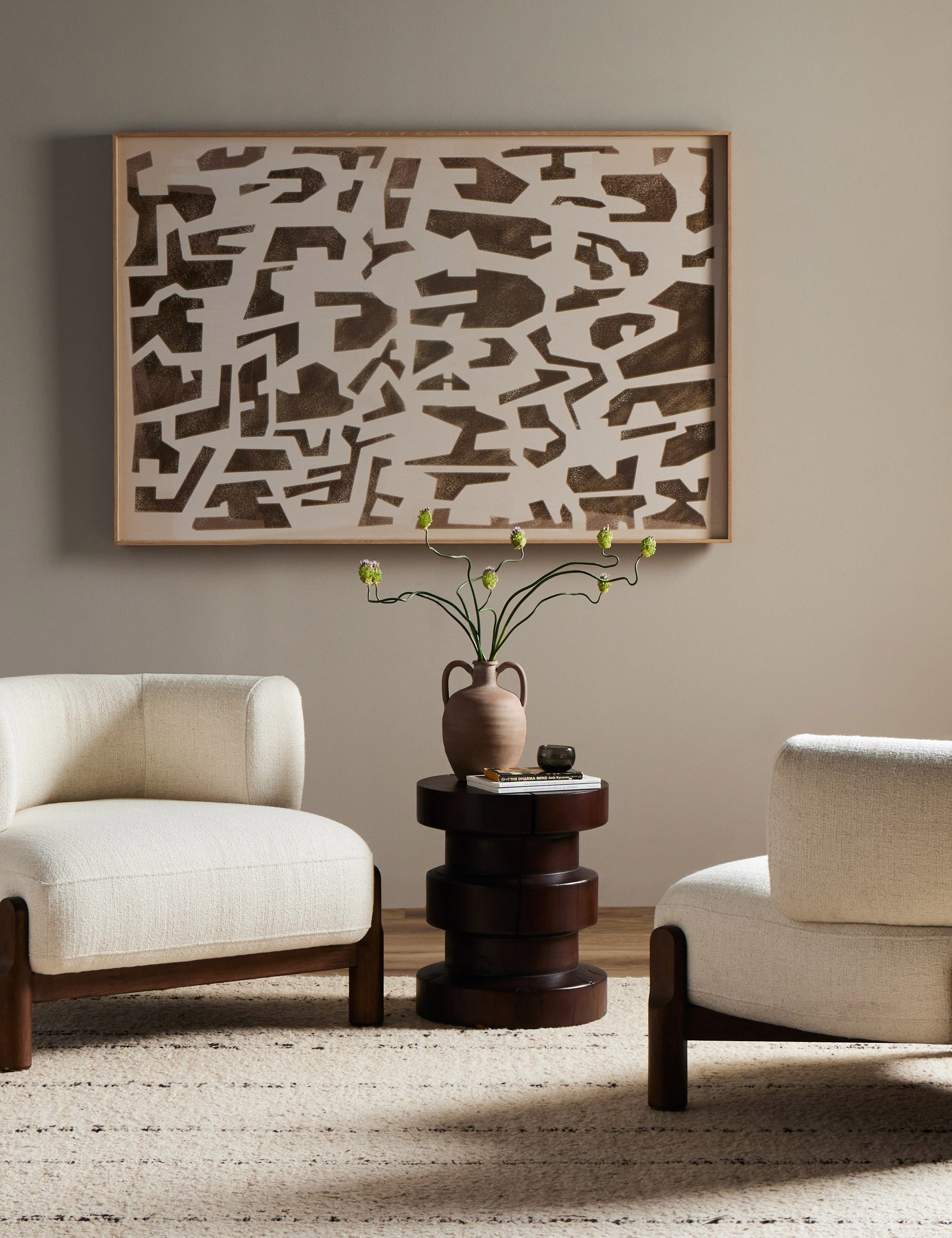 Two of the Furst sculptural upholstered barrel back accent chair in ivory styled with a round side table and modern wall art.