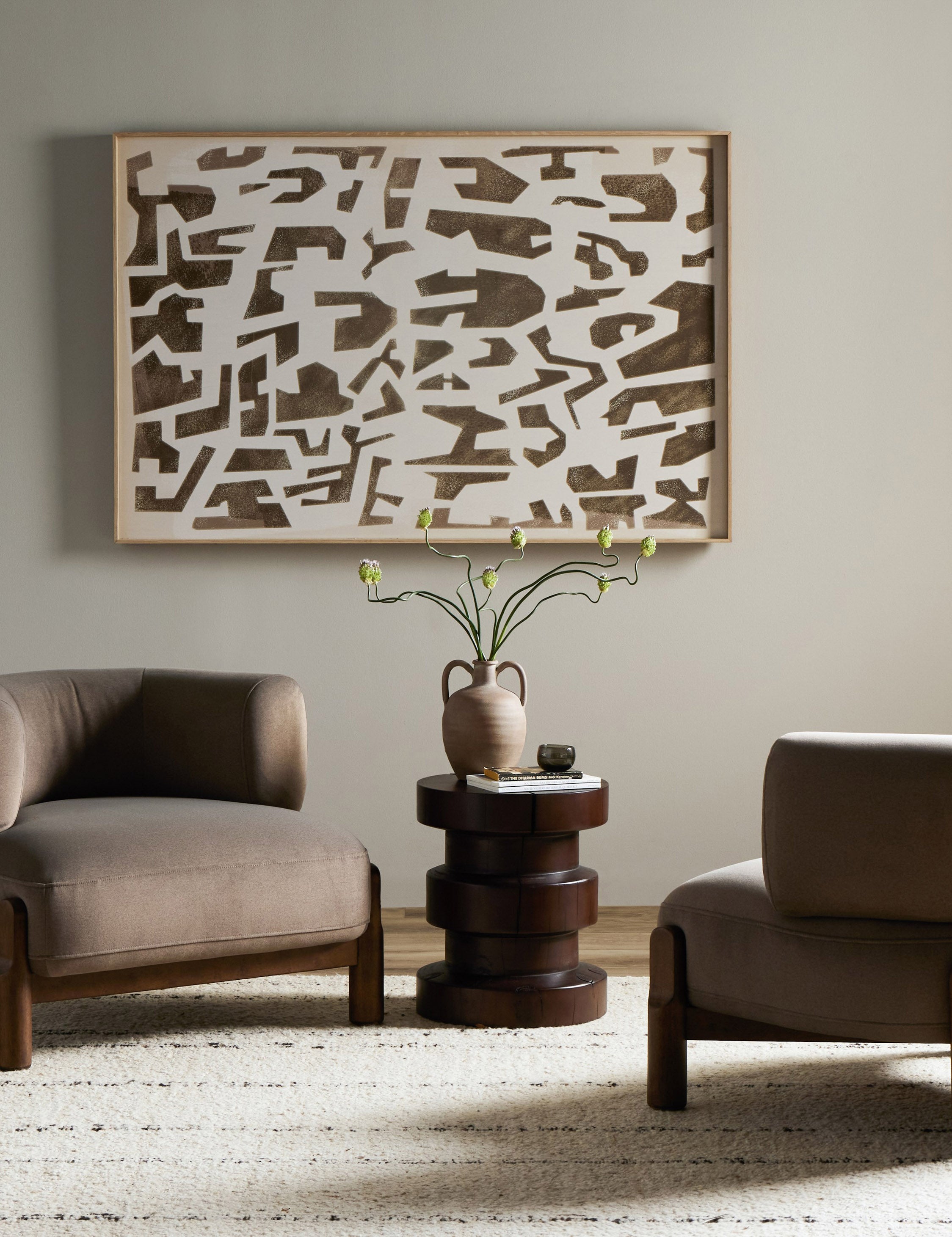 Two of the Furst sculptural upholstered barrel back accent chair in taupe velvet styled with a round side table and modern wall art.