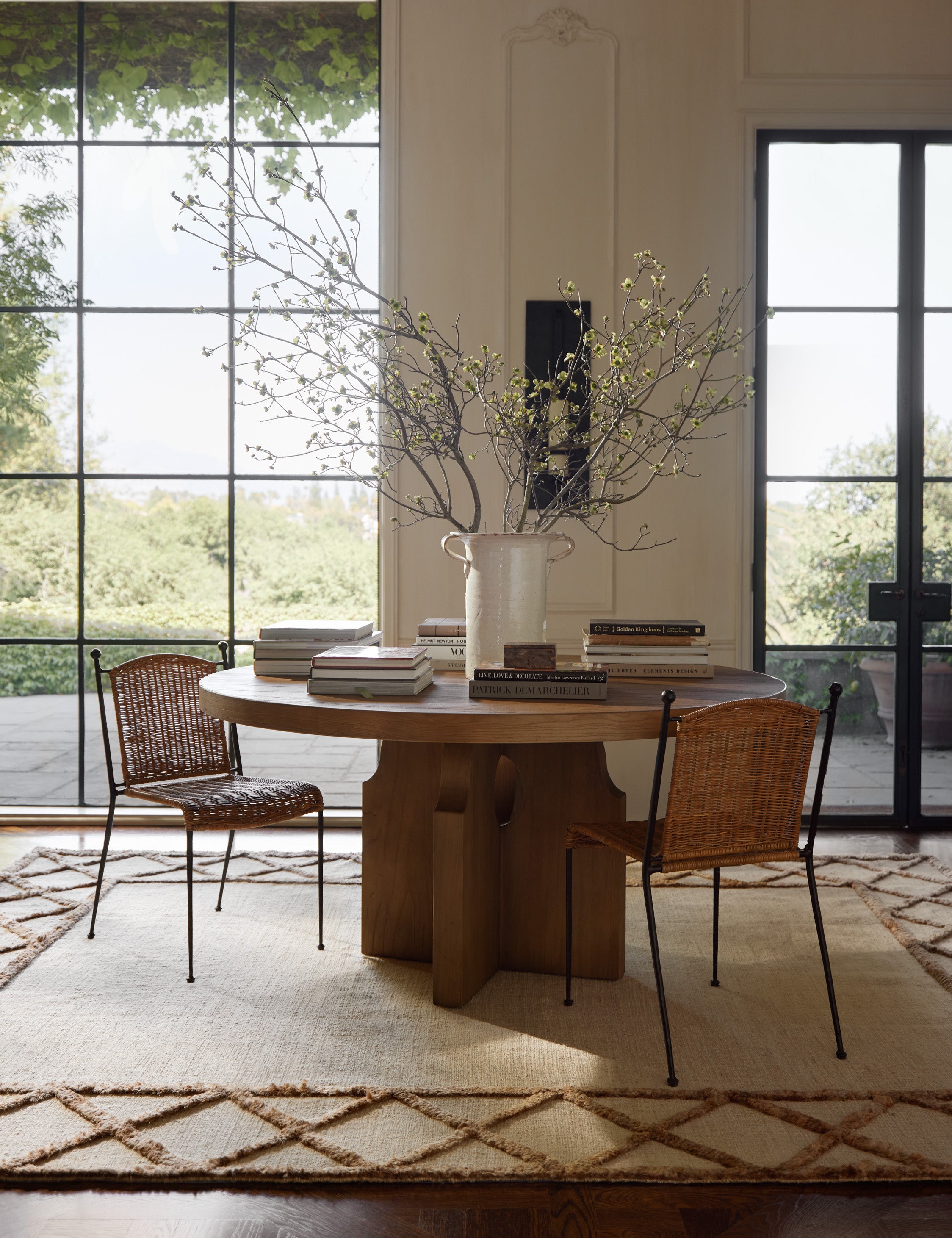 A round table and two chairs styled atop the Clairmont Handwoven Lattice Border Jute Rug by Jake Arnold