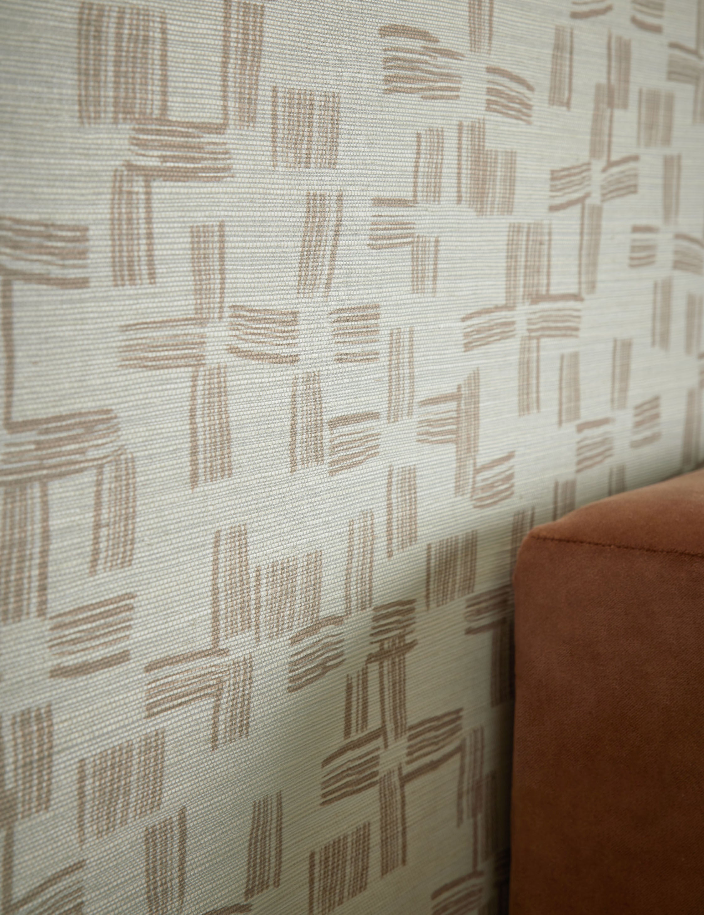 Angled view of the Crossmarks Grasscloth Wallpaper by Élan Byrd on a wall.
