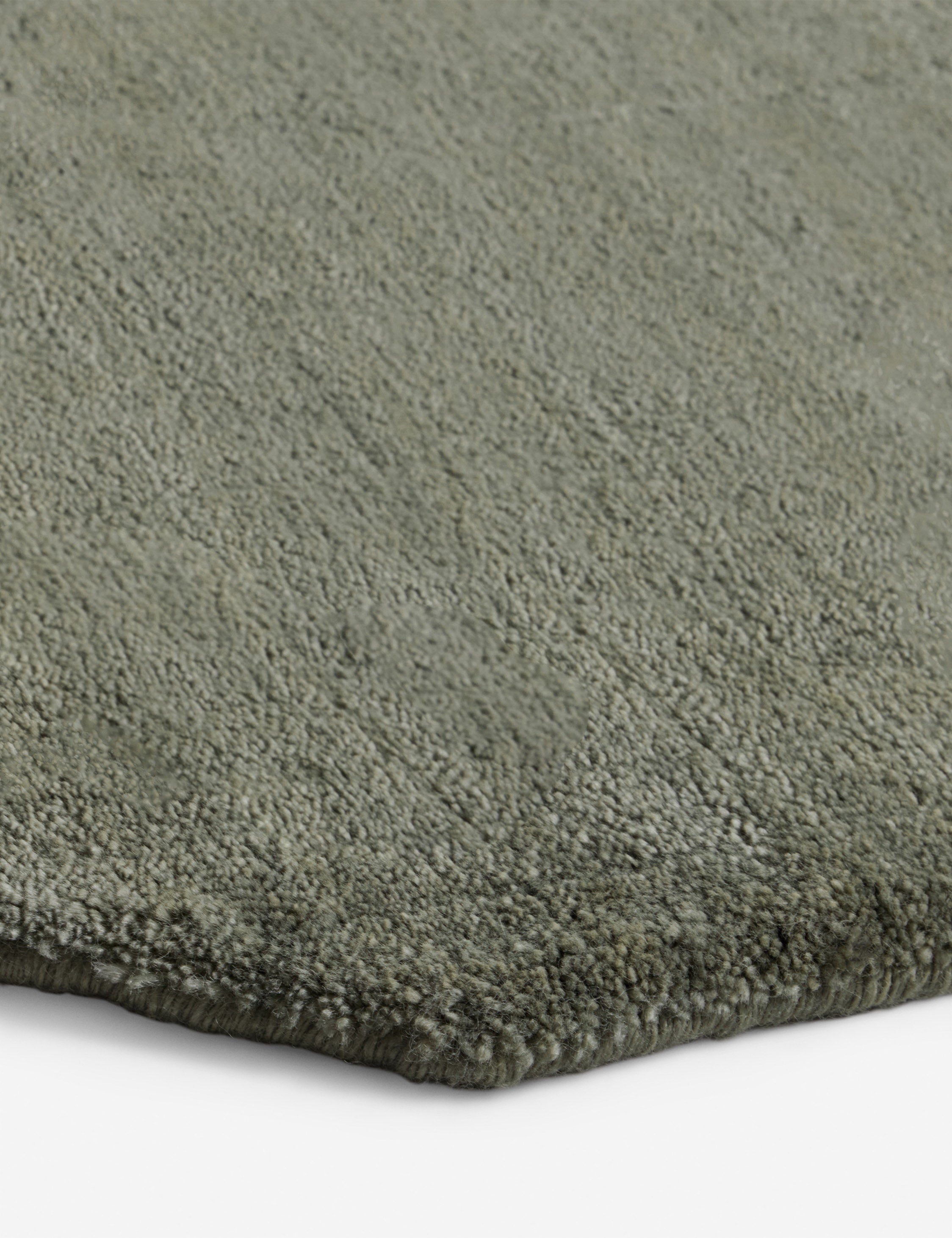 Close up of the corner of the Damara solid viscose rug in sage.
