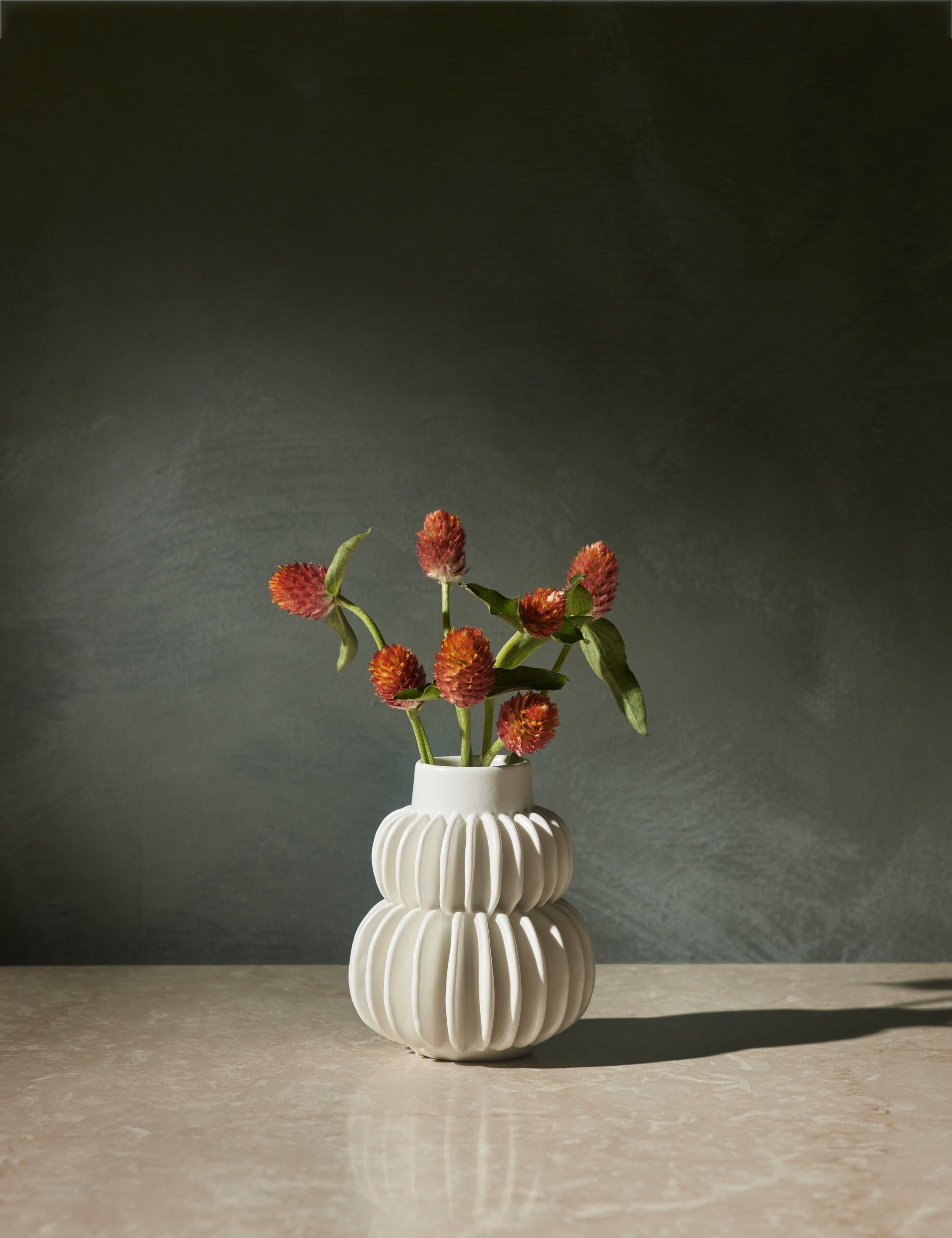 Delilah white ceramic vase featuring two rows of half-moon discs fanned around a tapered body with flowers inside of it