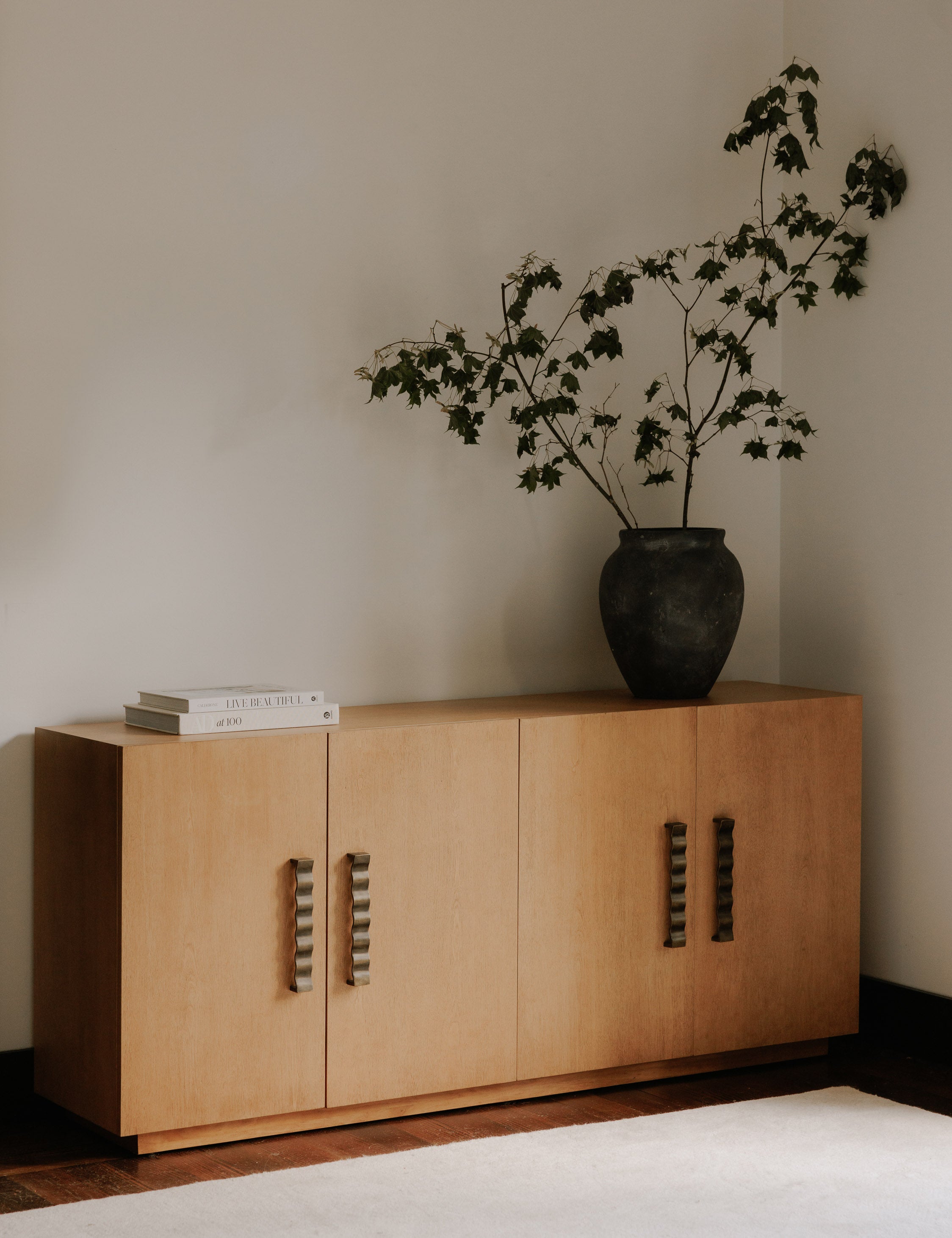 Fielder mid-century modern 4-door sideboard cabinet styled with a large black vase and white rug.