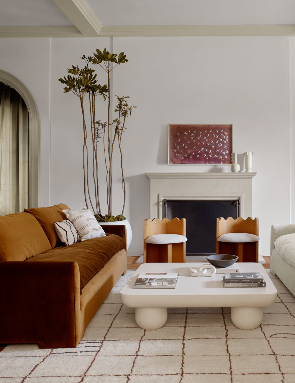 The Crane stencil 2 magenta and white wall art by ZBC house is hung above a fire place in a living room with sculptural furniture pieces