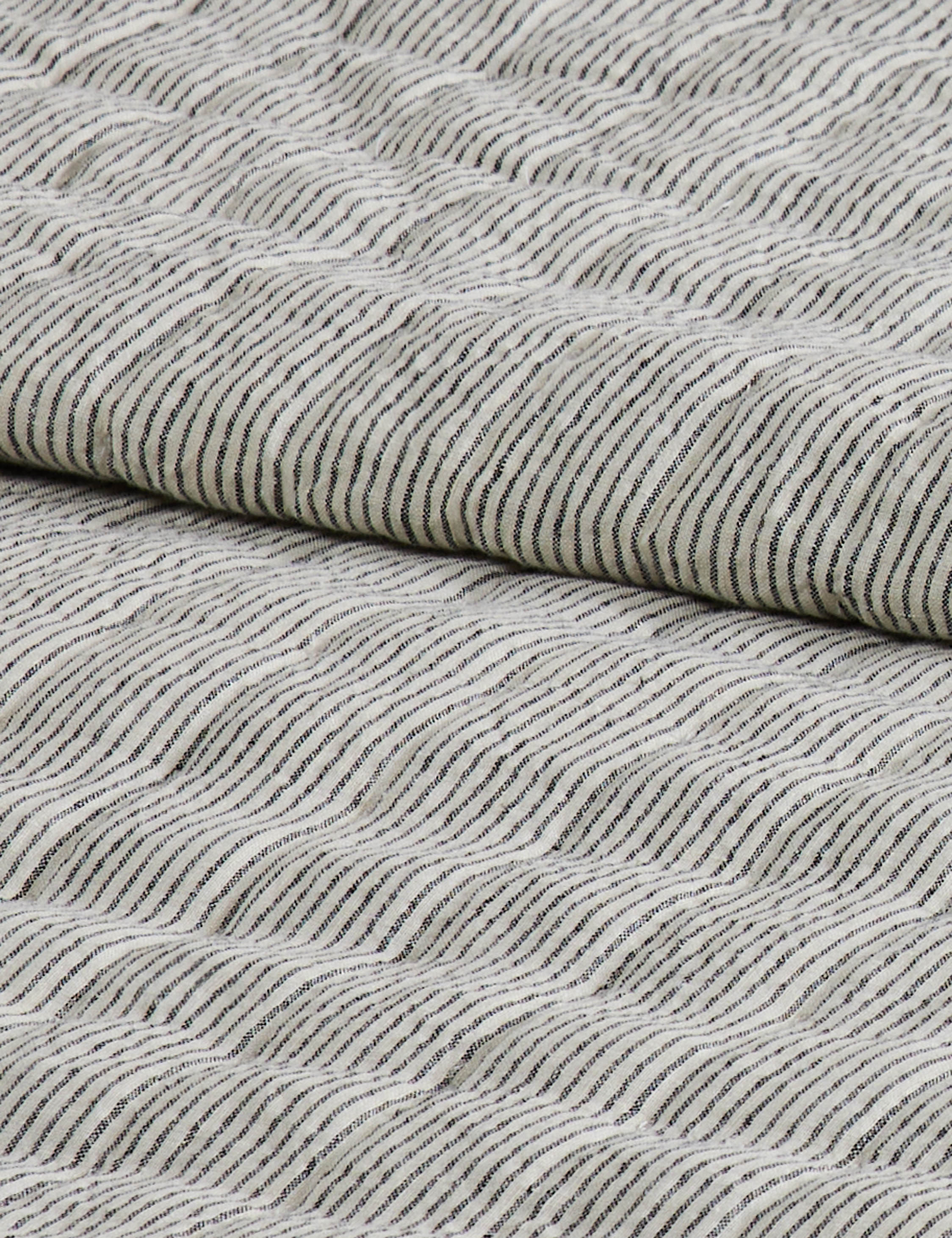 Close up of the Lammin striped quilted linen coverlet in black and ivory