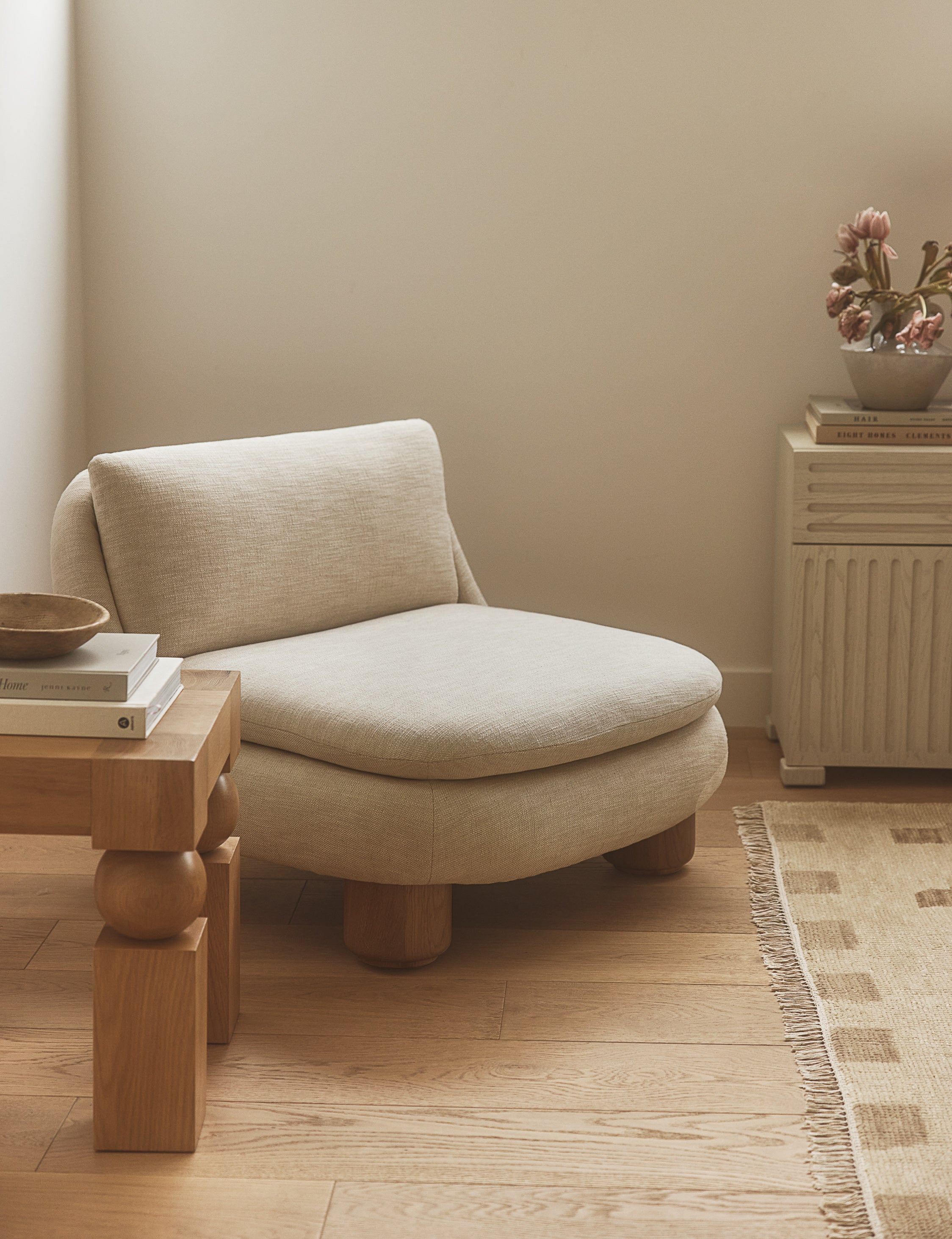 Lozano chunky low-profile armless accent chair styled in the corner of a bedroom.