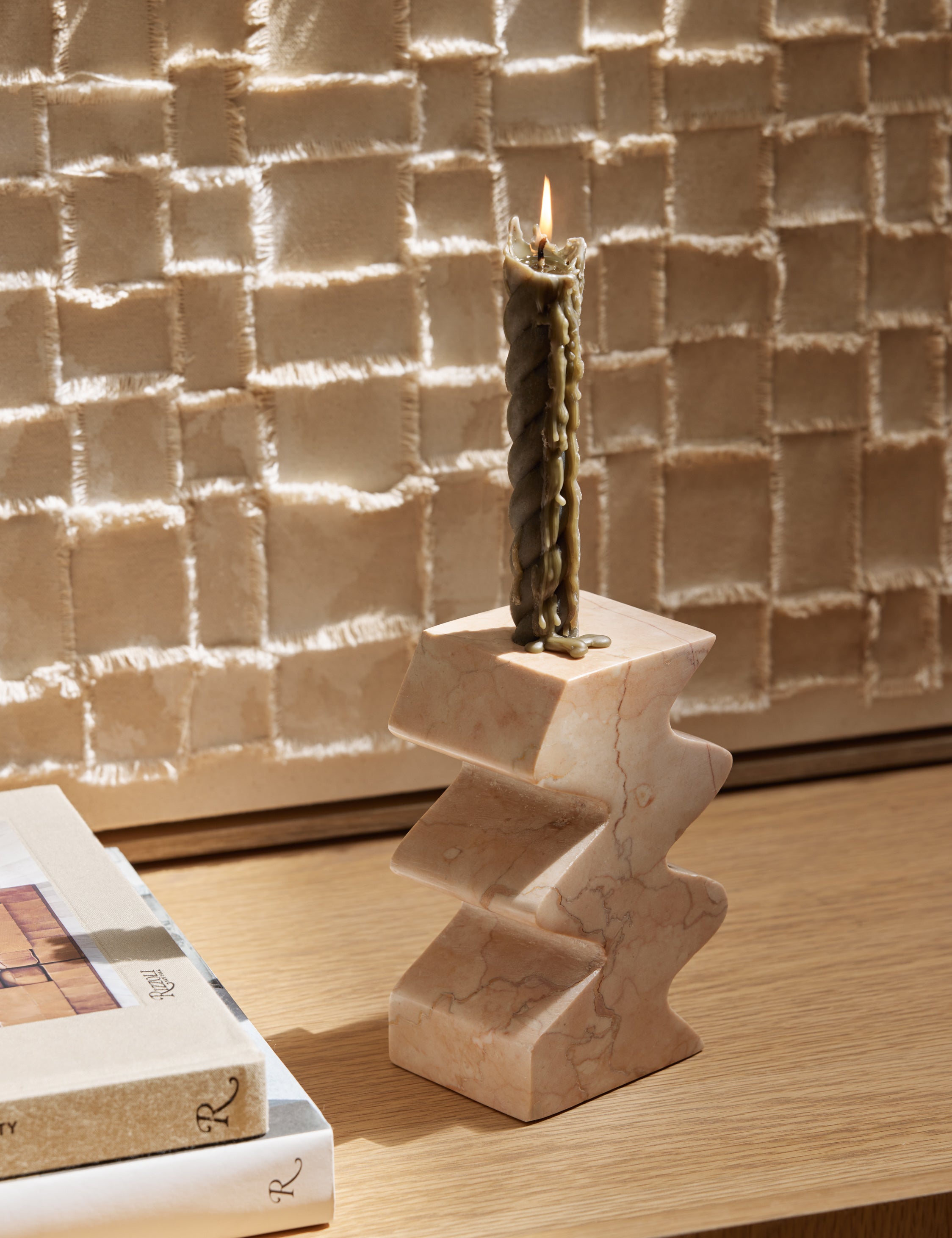 Mischa sculptural marble taper candle holder styled on a console table with a olive green taper.