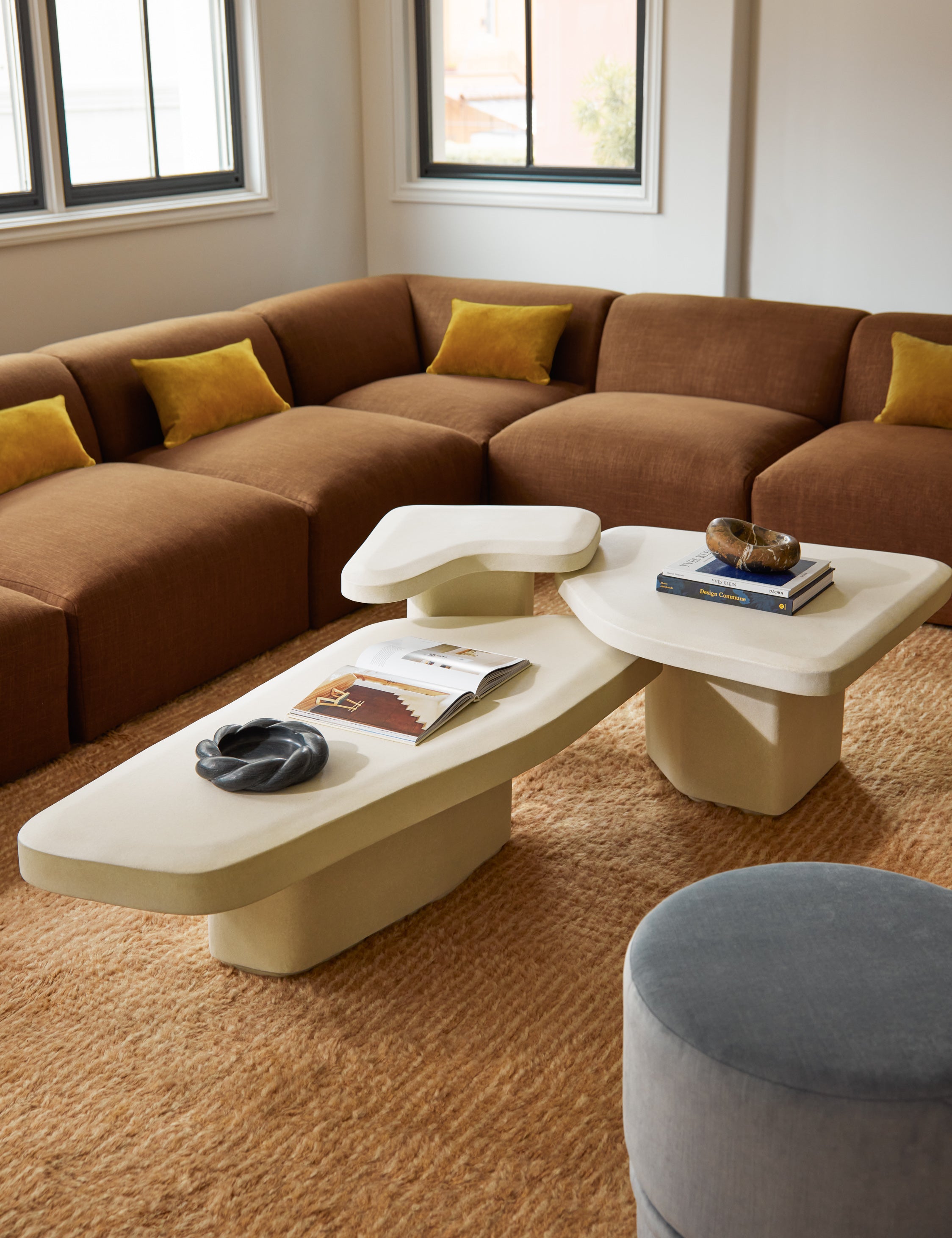 Cyprus striped, tasseled, Moroccan-styled wool rug styled with a modern corner sectional sofa and sculptural nesting coffee table.