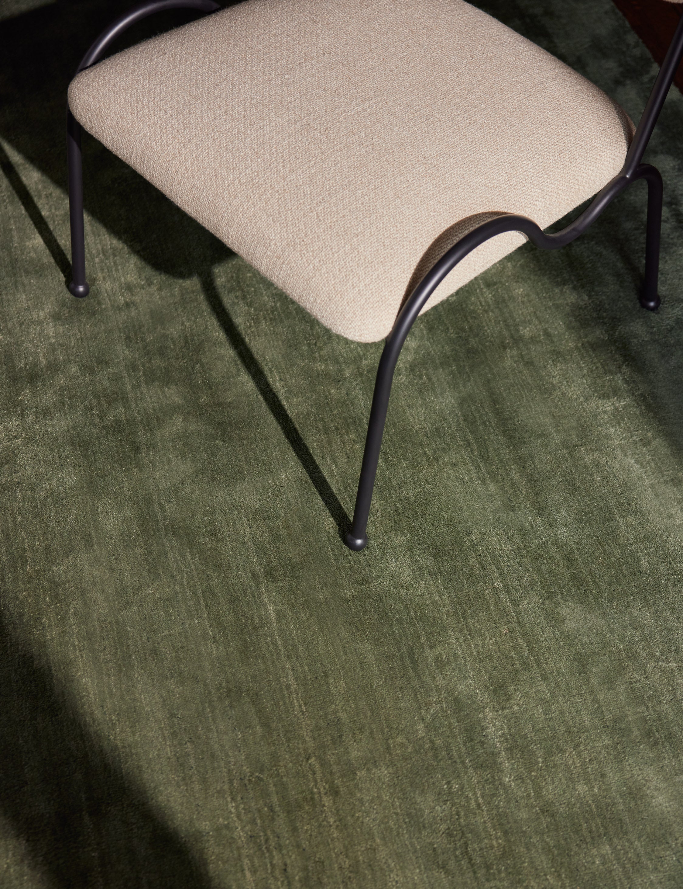 Close up view of the Sutton Solid Color Hand-Loomed Viscose Rug by Aimee Song under a dining chair