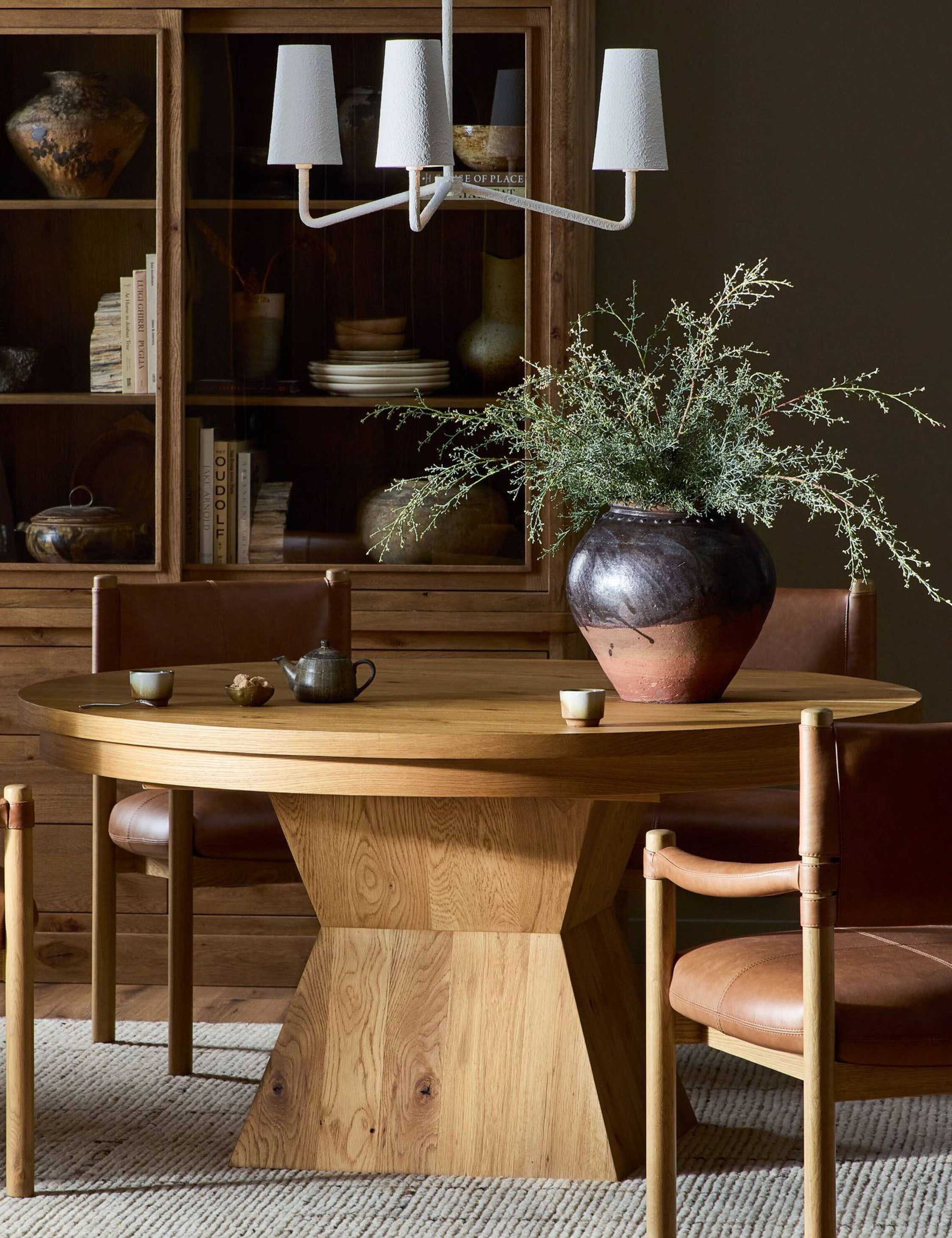 A dining room featuring the Hermoza sculptural round pedestal extendable dining table and leather upholstered dining chairs.