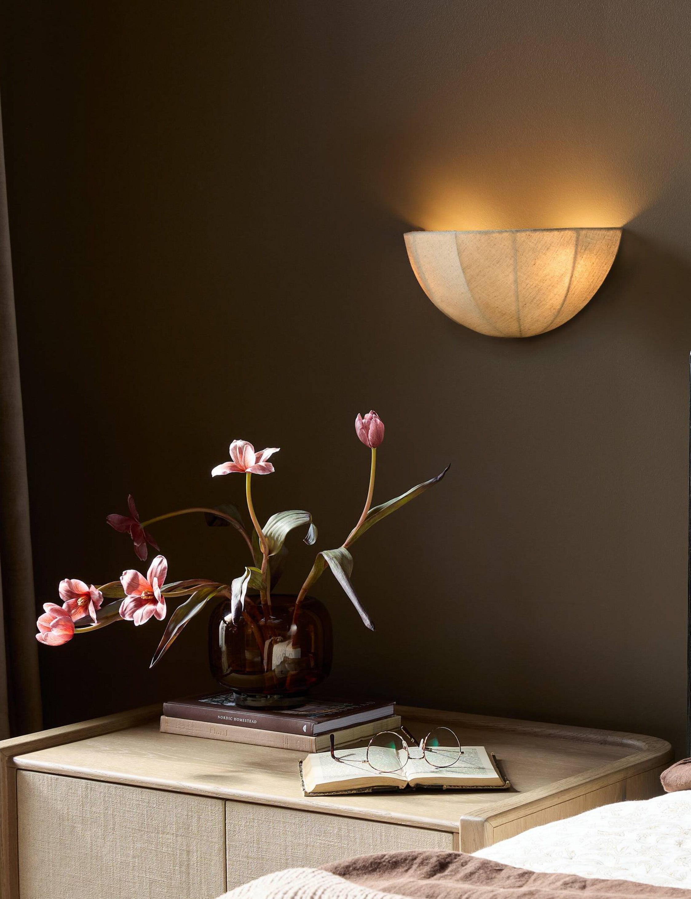 Mahan linen up-ight wall sconce hung above a nightstand