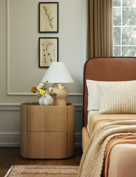 | Bedroom with the Raphael modern rounded natural wood two drawer nightstand next to a rust velvet upholstered bedframe