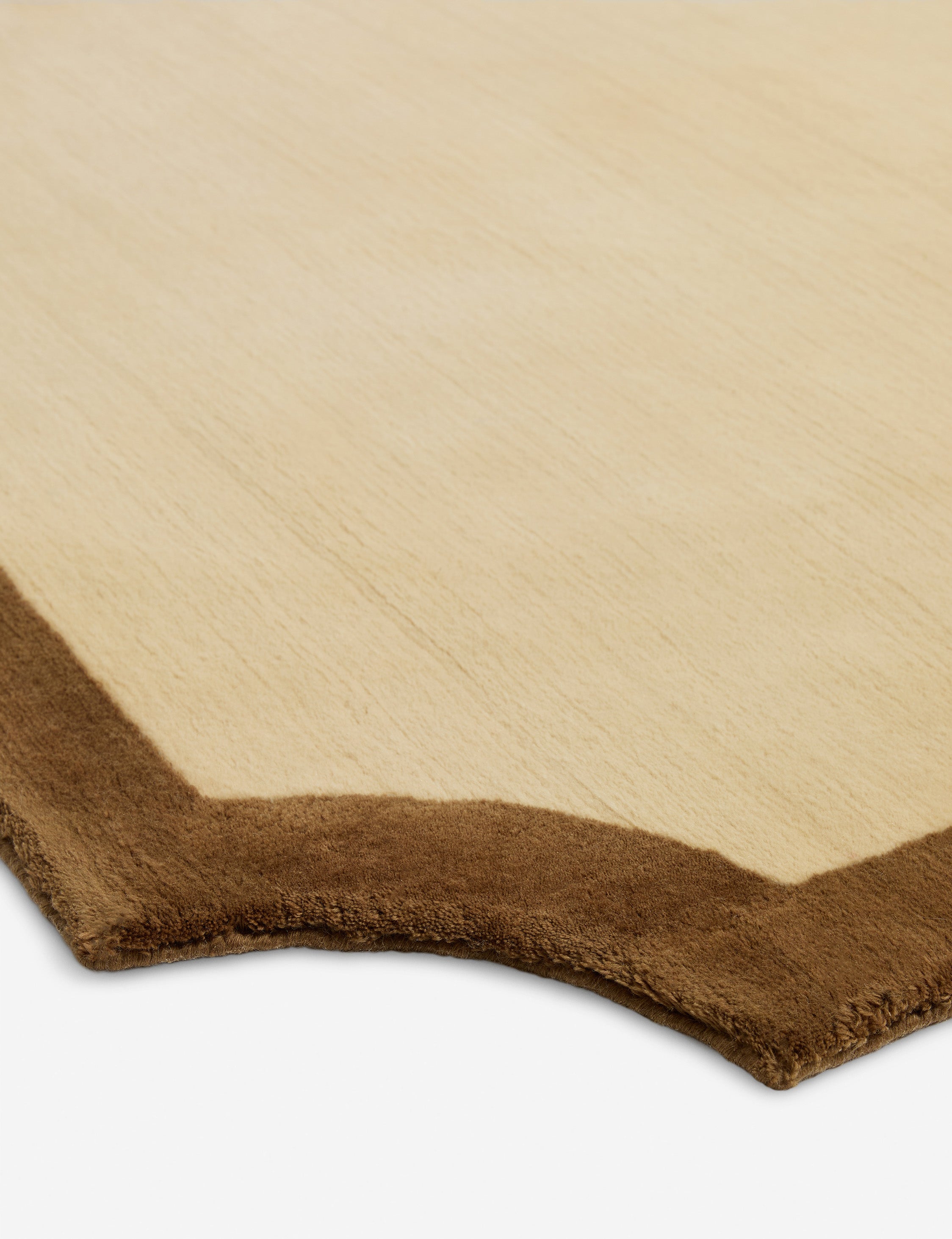 Close up view of the scalloped corner of the Clapham Hand-Loomed Wool Rug by Jake Arnold.