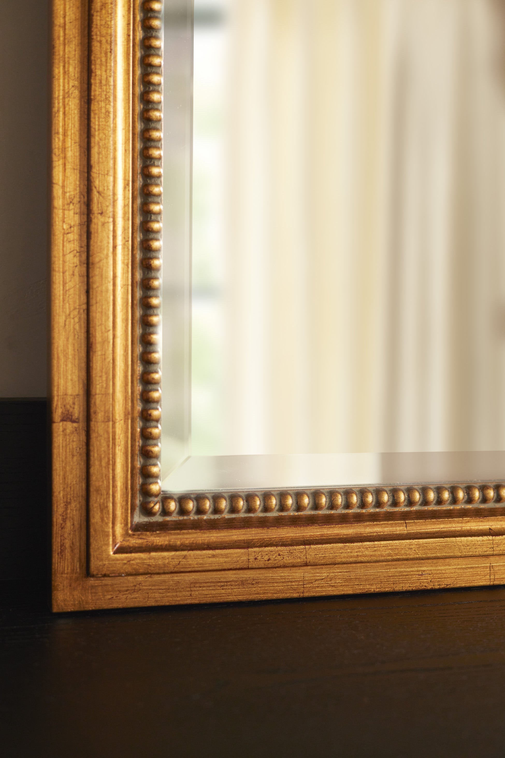 Bottom corner of the Corinne textural gold epoxy resin frame wall mirror.