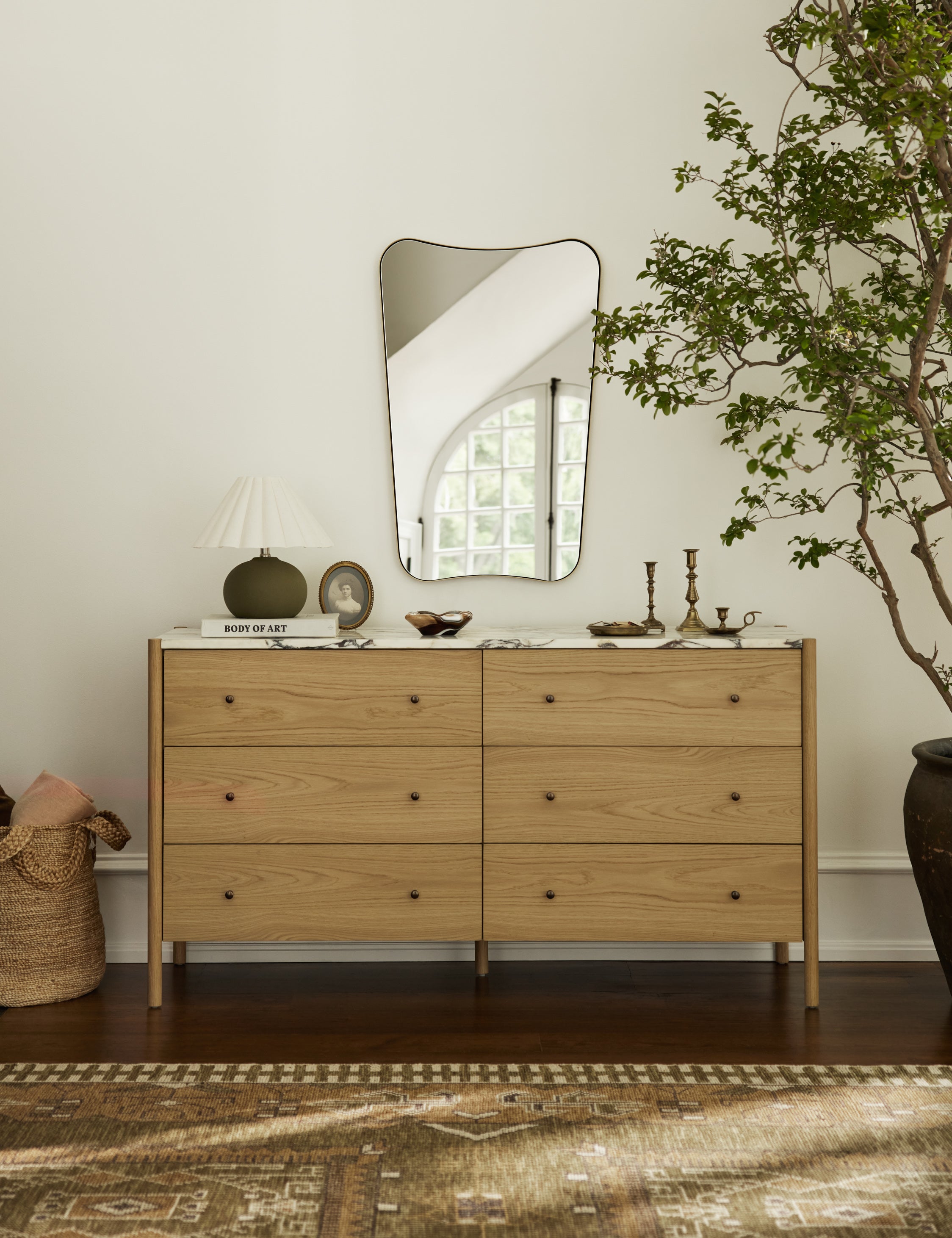 Belvoir thin brass framed wall mirror hanging above a dresser