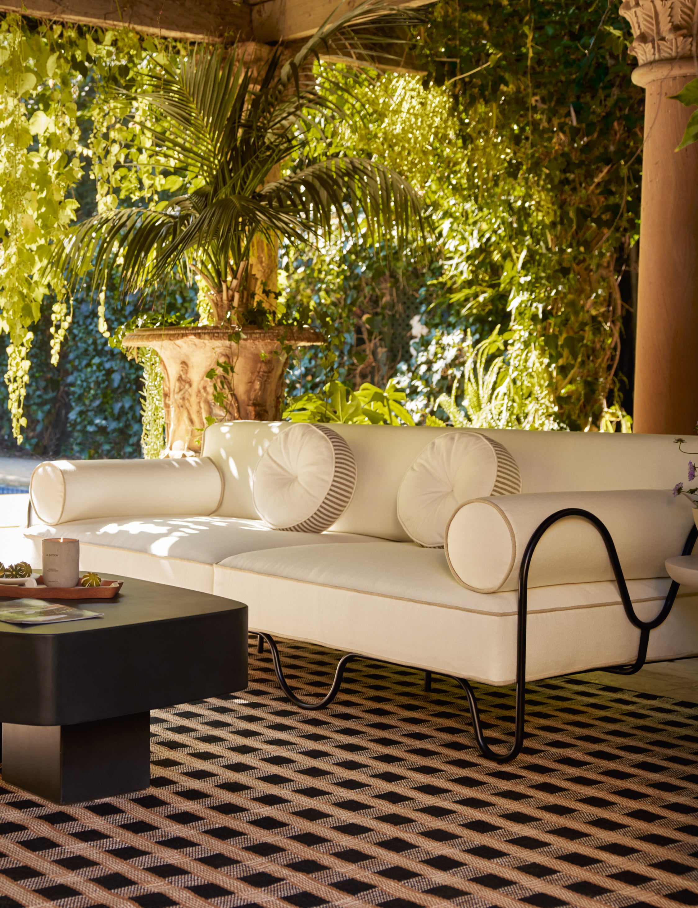 Littu Indoor / Outdoor Striped Disc Pillow by Sarah Sherman Samuel in Brown styled on an outdoor sofa.