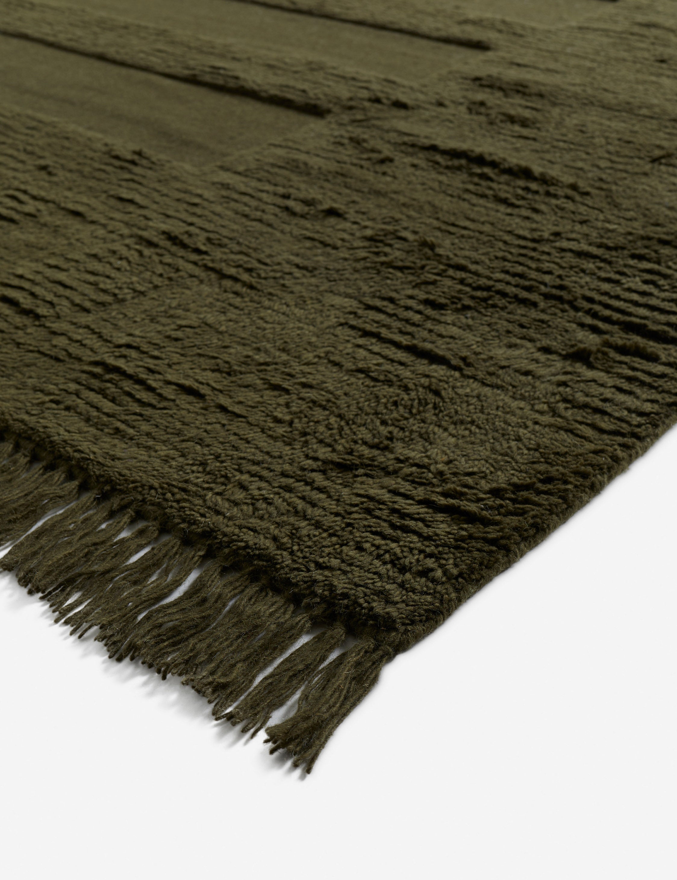 Corner of the Raita subtle bar patter fringe area rug in moss green