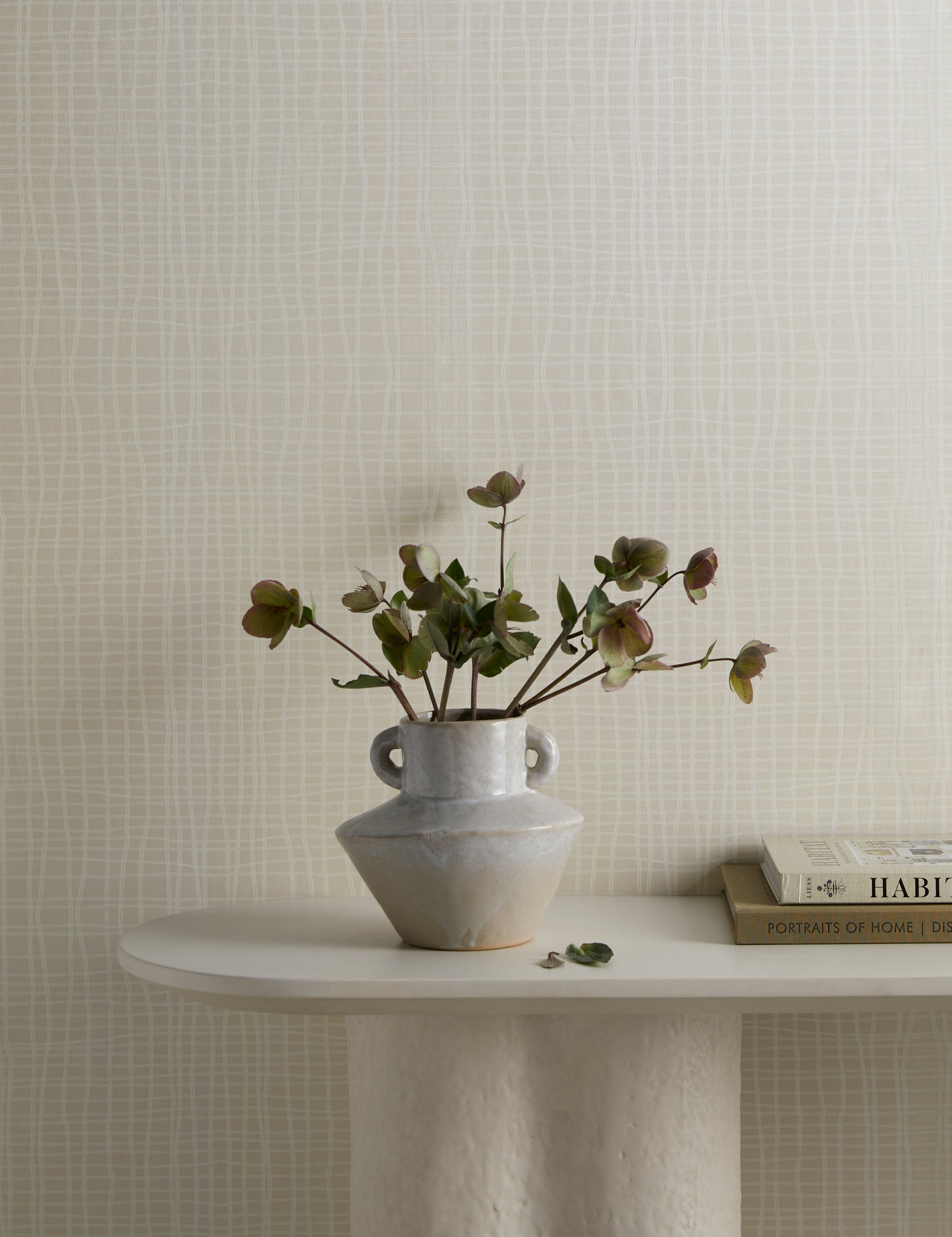 Seafarer Abstract Grid Wallpaper by Élan Byrd on a wall behind a console table styled with a vase filled with botanical stems.