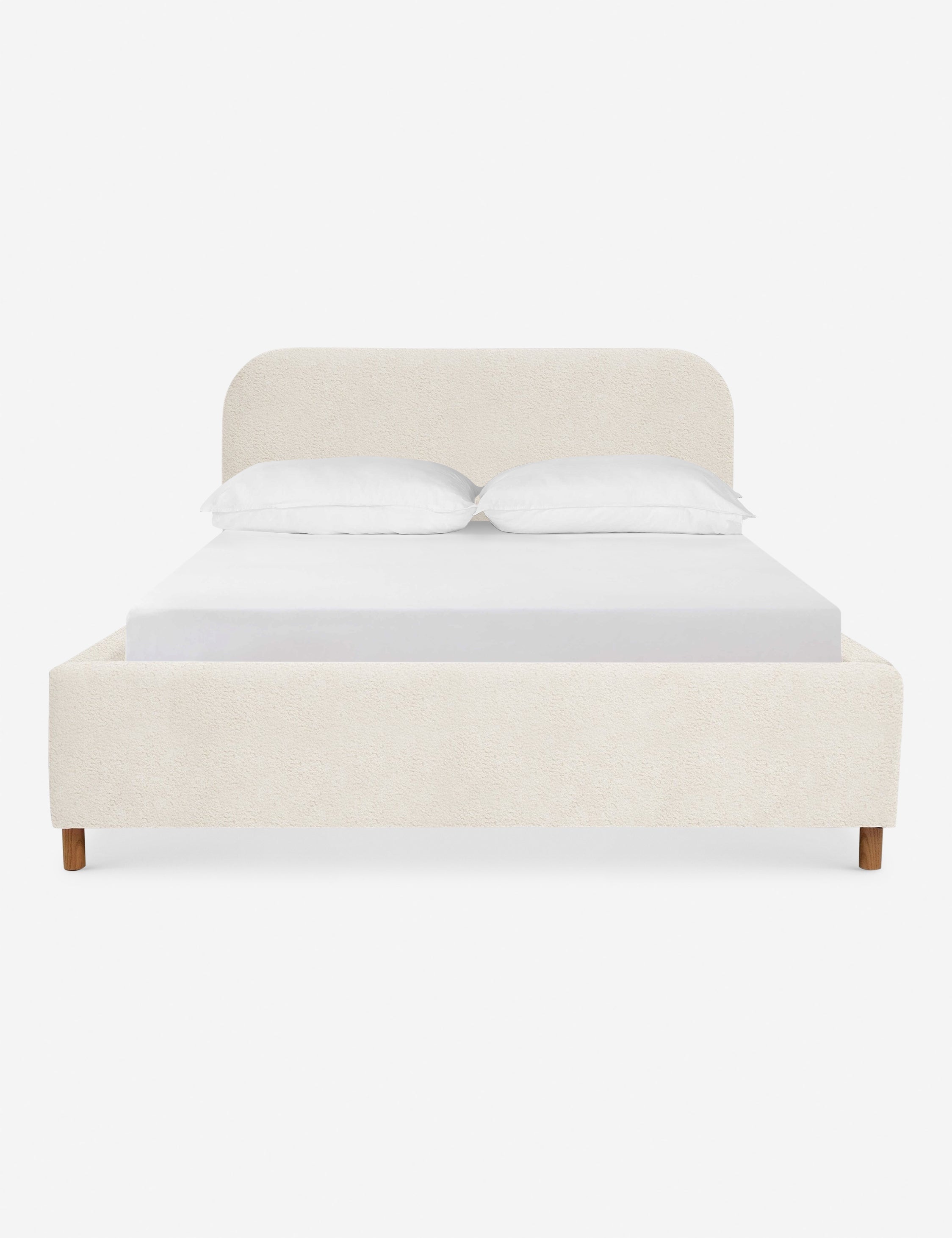Solene Boucle Cream platform bed with an arched headboard and oak wood legs