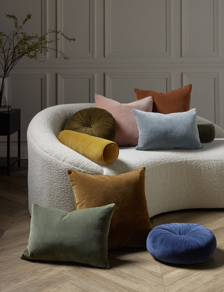 #color::toast #style::square  #fill type::with-feather-down-insert  #fill type::pillow-cover-only |   Charlotte velvet pillow in moss, rosewater, ice blue, burnt orange, and toast sit next to and on a cream boucle lounger