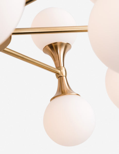 | Close-up of the a cone-shaped metal stand and dual-light fixture on the Abernathy gold wheel-like chandelier 