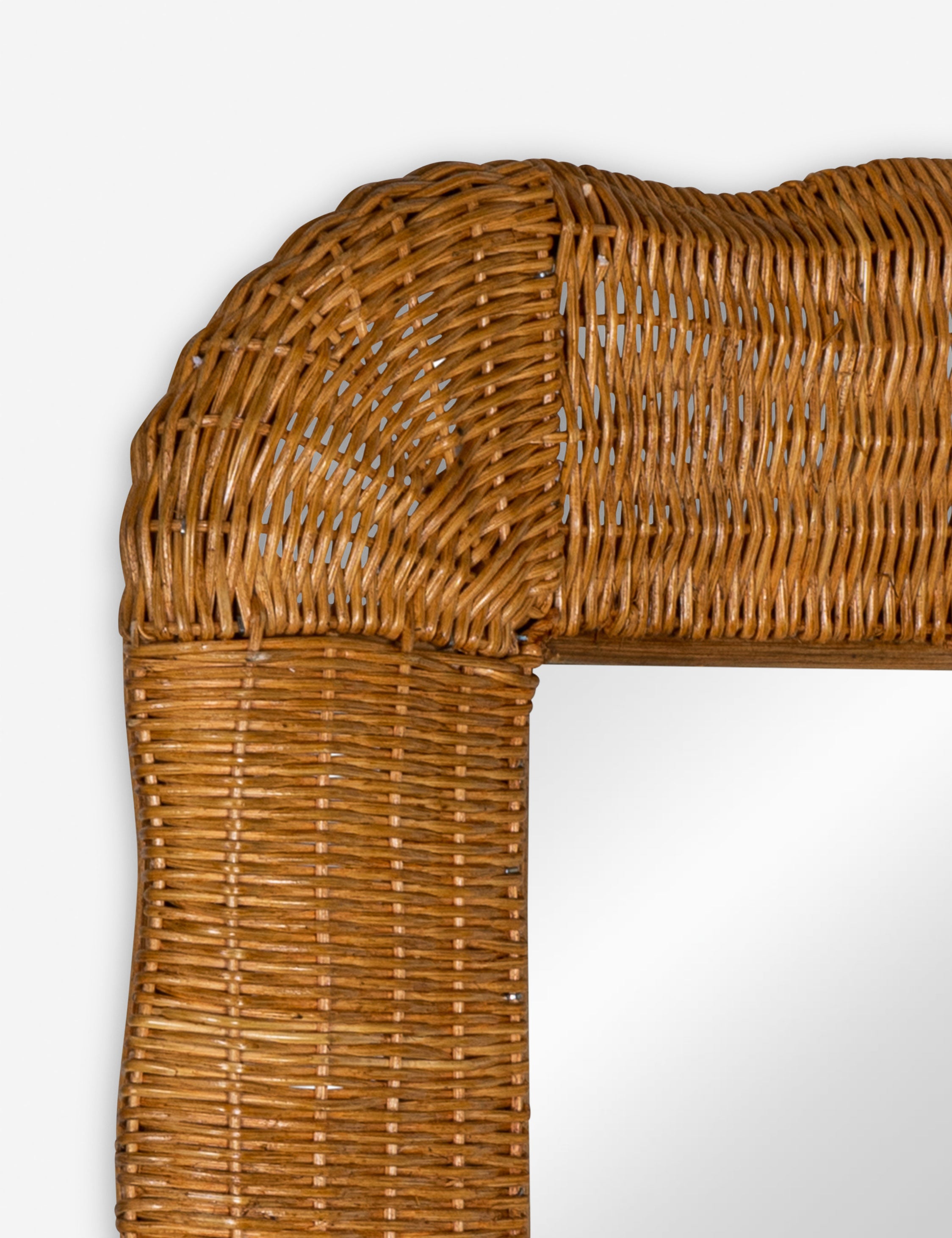 Close up of the corner of the Yarely woven rattan frame wall mirror.