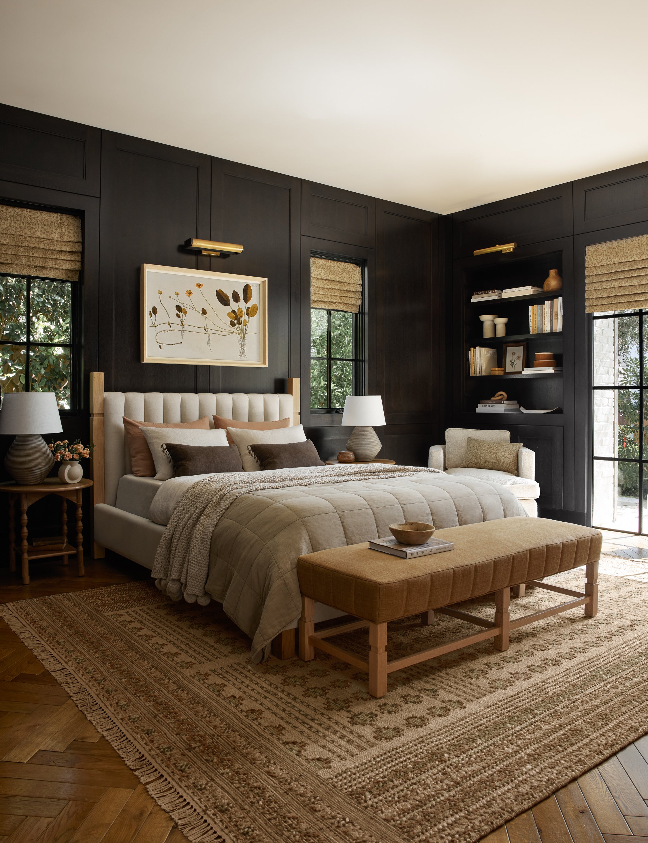  The Ambleside camel linen bench sits atop a patterned rug in a room with accented black wooden walls and a natural linen bed