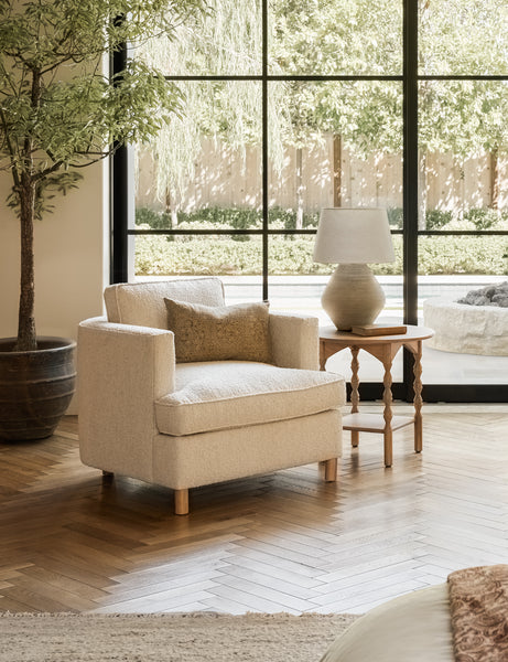 #showall::40199323451491 | The Belmont taupe boucle accent chair sits atop chevron wooden floors next to a round wooden side table with sculptural legs