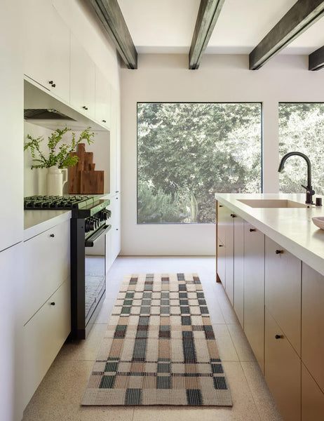#size::2-6--x-8- | The marli rug in its runner size lays in a kitchen with white cabinetry, black beamed ceilings, and large square windows