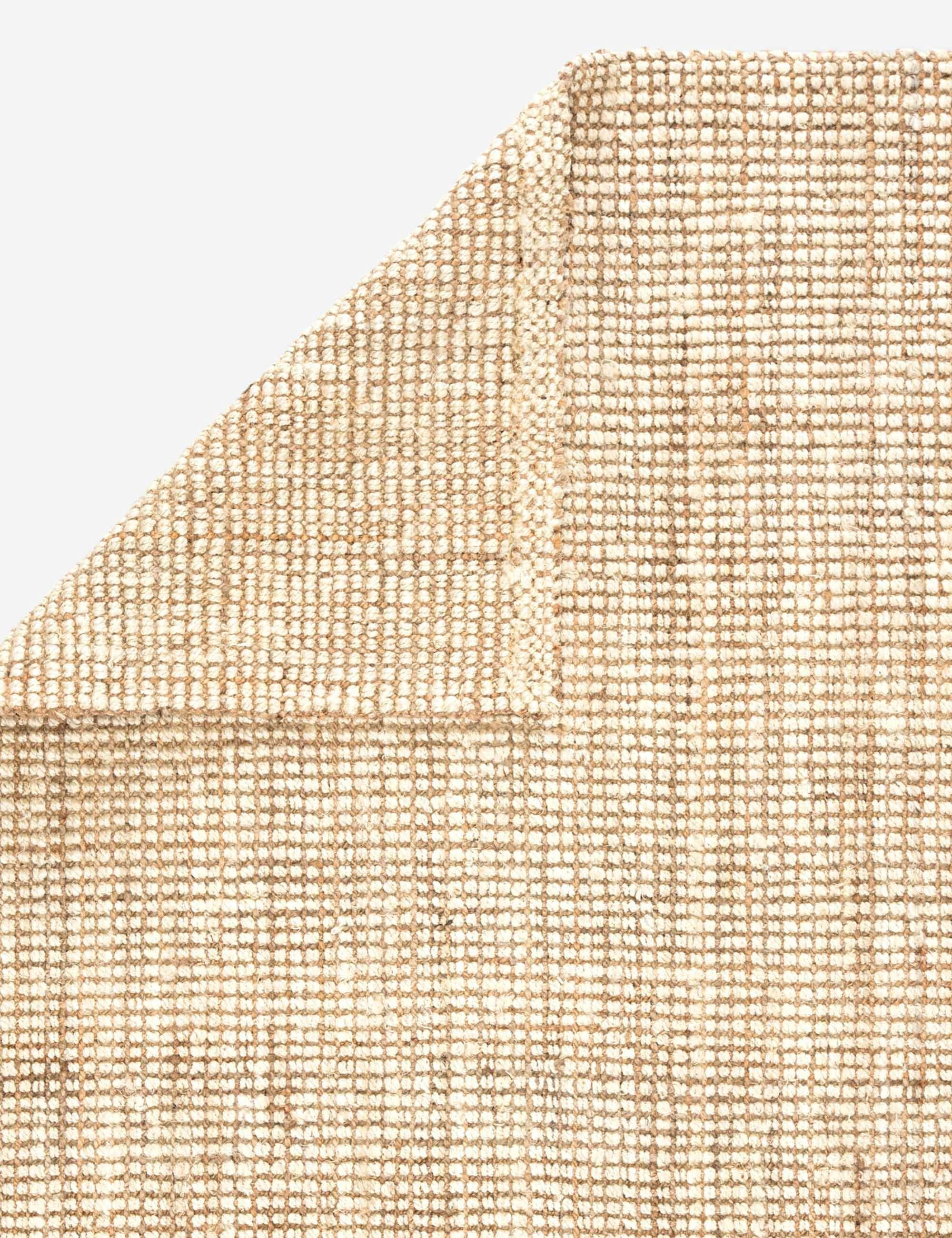 Close-up of the folded over corner of the Harriette scandinavian-inspired rug made of 100% jute