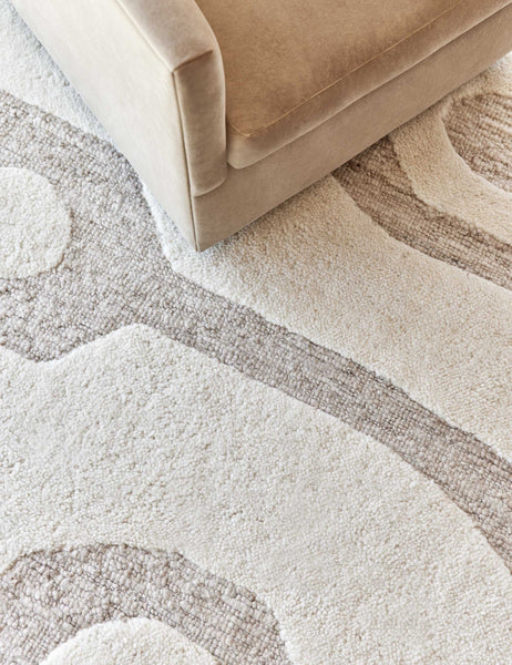 #size::6--x-9- #size::8--x-10- #size::9--x-12- #size::10--x-14- #size::12--x-15- | Close-up of the Oasis plush geometric neutral-toned rug by Élan Byrd underneath a light brown velvet sofa